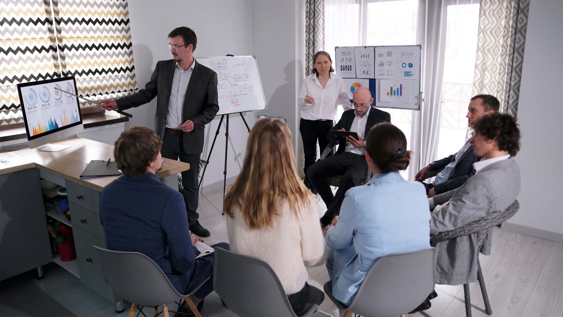 A group of people is sitting on chairs in a conference room and listening to a mentor's presentation. Coaching from a coach